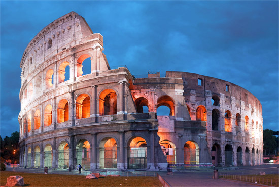 Colosseum lit up against dark night sky, Rome, Italy